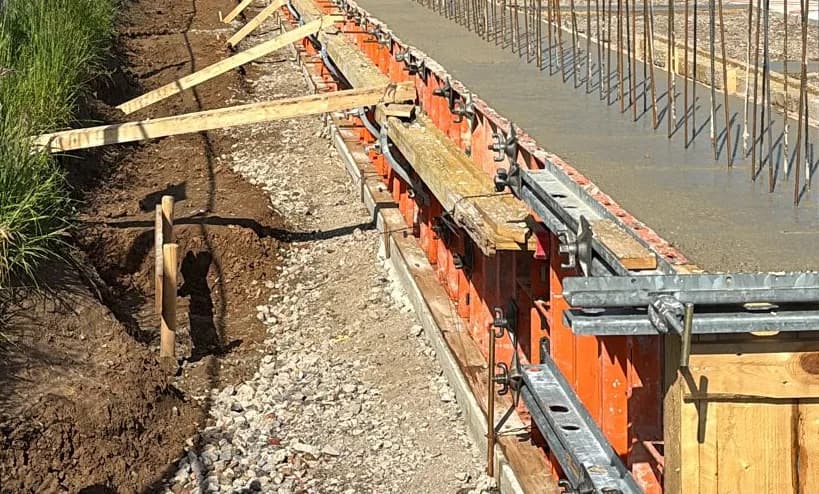 Rohbau: Fundamentbetonage — frischer Beton in der Schalung mit Anschlussbewehrung